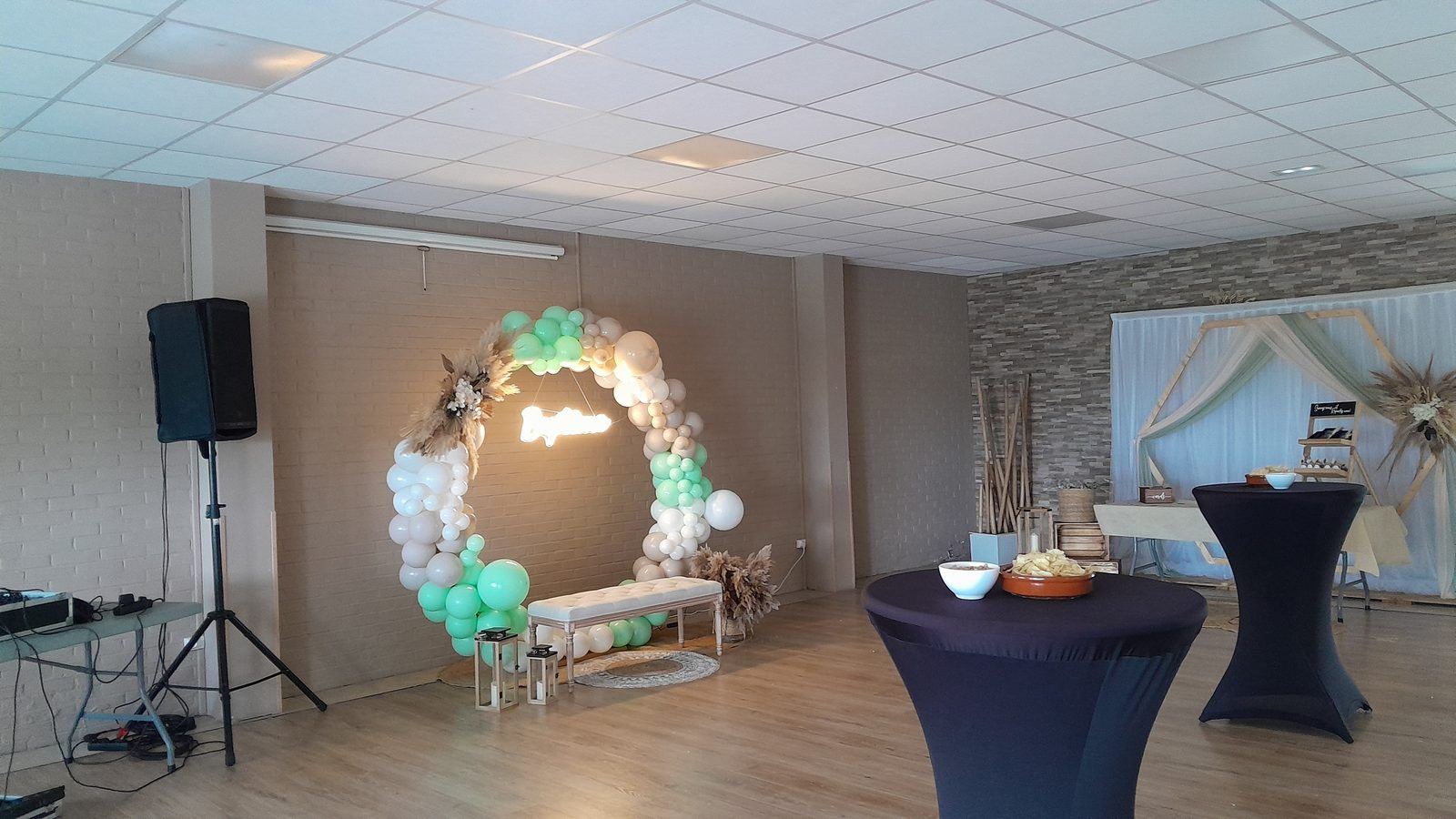 Salle décorée avec arche de ballons et mange-debout