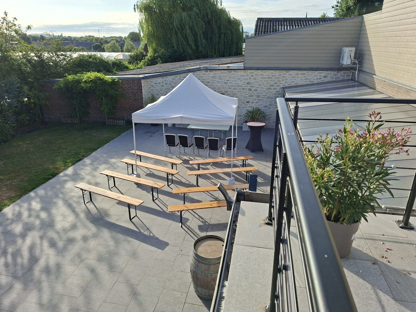 Terrasse privée aménagée en configuration séminaire avec assises en rangées sous barnum